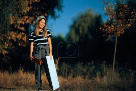Woman Holding a Canvas and an Easel Ready to Paint Outdoors 