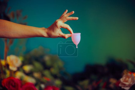 Foto de Mano sosteniendo una copa menstrual sobre un fondo floral - Imagen libre de derechos