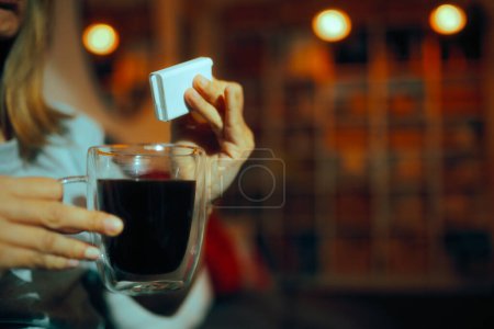 Foto de Persona usando edulcorante artificial en su café negro - Imagen libre de derechos