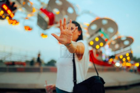 Mädchen macht Stopp-Geste mit der Handfläche auf einem Jahrmarkt 