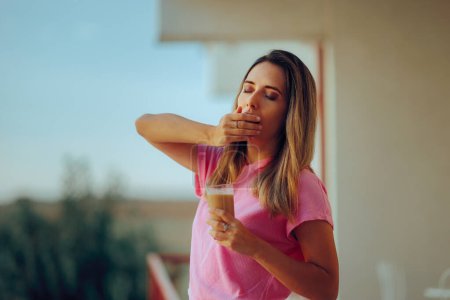 Gähnende Frau mit kaltem Kaffee im Glas