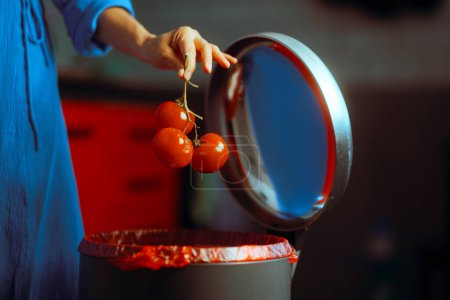 Personne qui jette des tomates gâtées dans la poubelle