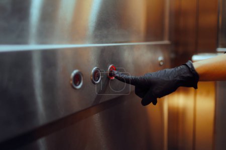 Persona germofóbica se pone guantes para tocar los botones del elevador