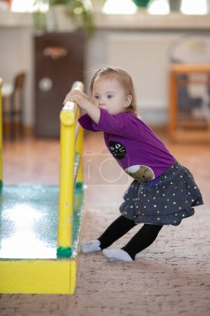 Photo for A girl with Down syndrome learns to stand up on her own. First independent steps - Royalty Free Image