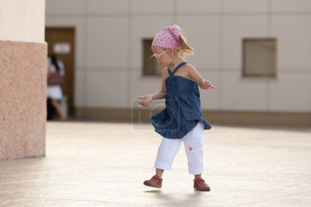 Photo for A girl with Down syndrome walks in the square. First independent steps - Royalty Free Image