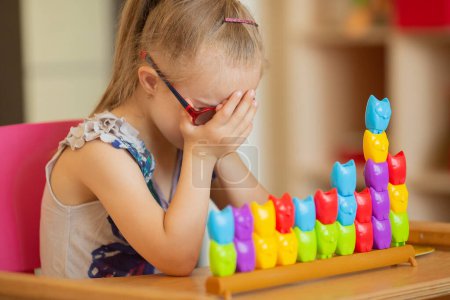 Téléchargez les photos : A beautiful smart girl with Down syndrome learns to sort by colors. elementary mathematics - en image libre de droit