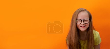 Photo for Happy girl with Down syndrome. Having fun, laughing. Funny pigtails. Studio. Portrait on a orange background. Banner - Royalty Free Image