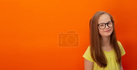 Téléchargez les photos : Happy girl with Down syndrome. Having fun, laughing. Funny pigtails. Studio. Portrait on a orange background. Banner - en image libre de droit