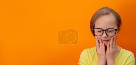 Téléchargez les photos : Happy girl with Down syndrome. Having fun, laughing. Funny pigtails. Studio. Portrait on a orange background. Banner - en image libre de droit