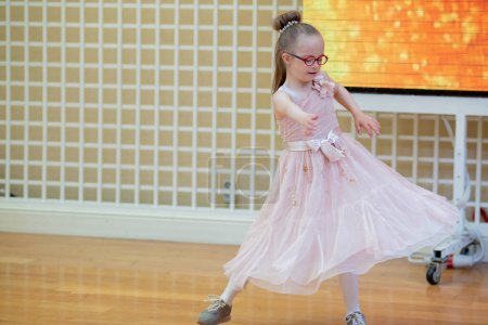 Téléchargez les photos : A girl with Down syndrome listens to music and dances. Nice dress - en image libre de droit