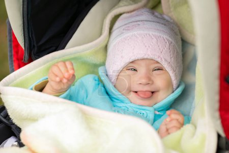Téléchargez les photos : Portrait d'une fille positive atteinte du syndrome de Down. Fait des visages et sort la langue - en image libre de droit