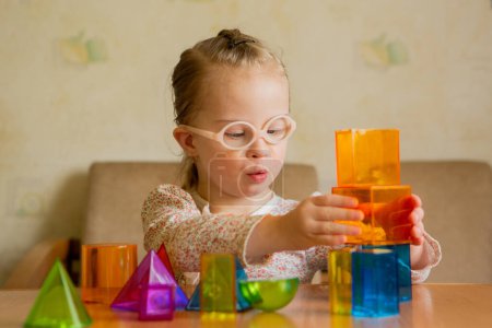 A girl with Downs syndrome lays out geometric shapes at home