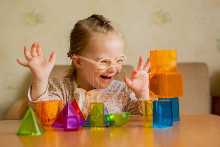 Téléchargez les photos : A girl with Downs syndrome lays out geometric shapes at home - en image libre de droit