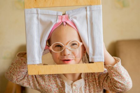 Téléchargez les photos : A girl with Down syndrome develops fine motor skills. Self-service skills Zip up clothes - en image libre de droit