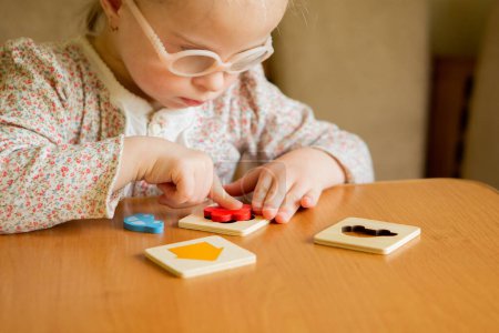 Photo for A girl with Down syndrome develops fine motor skills. learning to assemble puzzles - Royalty Free Image