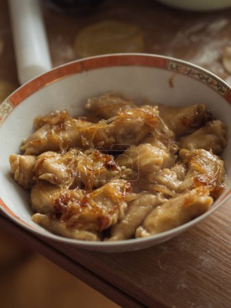 Foto de Vertical primer plano de varenyky ucraniano, albóndigas similares a ravioles italianos, con cebollas caramelizadas en la parte superior en un plato en una mesa de cocina. - Imagen libre de derechos