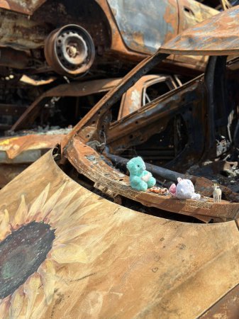 Téléchargez les photos : Un jouet pour enfants sur une voiture incendiée. La voiture a été endommagée par l'explosion d'un obus militaire. Déversement de voitures explosées et brûlées. Ukraine, Irpin, 6 juin 2023 - en image libre de droit