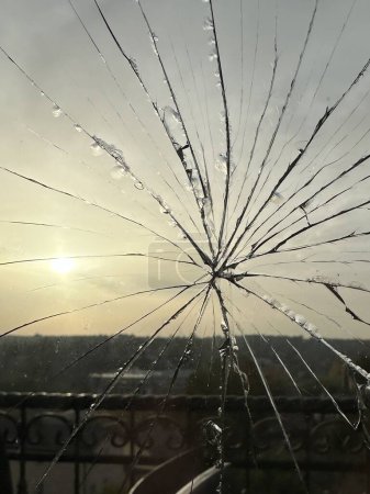 Foto de Vidrio agrietado en una ventana contra el fondo del sol. Grietas en una ventana de doble acristalamiento. Ventana rota en interiores. - Imagen libre de derechos