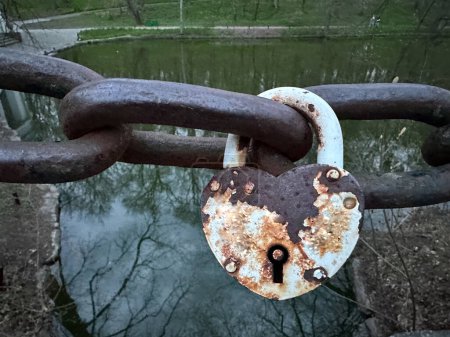 The padlock is fastened to a rusty chain. Old powerful castle in the shape of a heart. Concept: love is forever, we are inseparable together