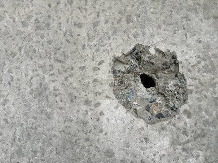 Hintergrund: ein Loch im Beton durch einen Schuss. Die Betonwand wird von einer Kugel durchbohrt. Schussspuren an der Wand, Nahaufnahme.