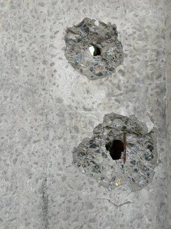 Hintergrund: ein Loch im Beton durch einen Schuss. Die Betonwand wird von einer Kugel durchbohrt. Schussspuren an der Wand, Nahaufnahme.
