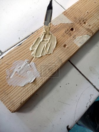 Application d'un mastic polyester sur un trou en bois avec une spatule