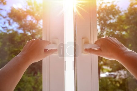 Mann zu Hause öffnet Fenster an einem sonnigen Tag. manuell geöffnetes weißes PVC-Kunststofffenster zu Hause