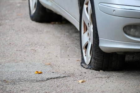 Close-up of a flat front tire. Car with a punctured wheel on a residential street. accident concept.