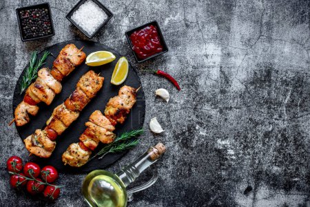 Photo for Grilled chicken on skewers with vegetables and spices on a black stone background - Royalty Free Image