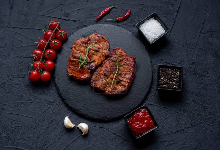 Téléchargez les photos : Steak de bœuf grillé aux légumes et épices sur fond noir - en image libre de droit