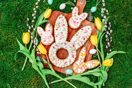 Foto de Galletas en forma de conejo de Pascua con huevos, flores de sauce y tulipanes - Imagen libre de derechos