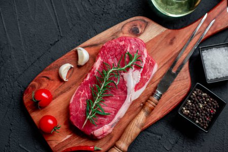 Photo for Raw beef steak with spices and herbs on black background. top view - Royalty Free Image