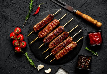Photo for Grilled sausages with spices and herbs on black granite plate - Royalty Free Image