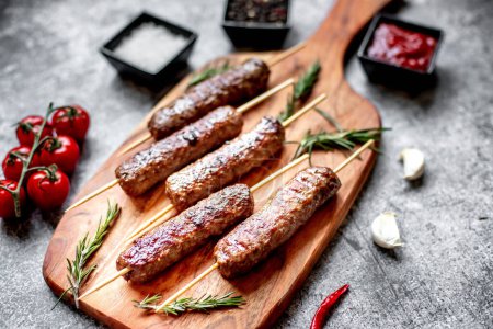 Photo for Grilled sausages with rosemary and spices on a wooden background - Royalty Free Image