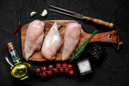 Photo for Three raw chicken breasts on black stone background - Royalty Free Image