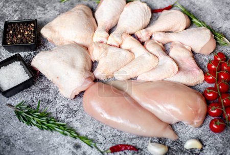 Foto de Conjunto de filetes de pollo crudo, muslos, alas y piernas sobre un fondo de piedra, vista superior - Imagen libre de derechos