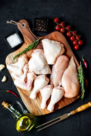Téléchargez les photos : Ensemble de filets de poulet crus, cuisses, ailes et pattes sur planche de bois - en image libre de droit