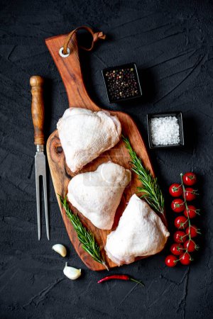 Téléchargez les photos : Cuisses de poulet crues sur fond de pierre noire - en image libre de droit