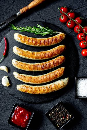 Photo for Grilled sausages on black stone background, top view - Royalty Free Image