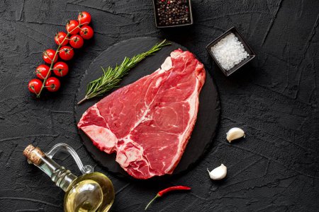 Téléchargez les photos : Steak de bœuf cru avec épices et herbes sur fond noir. vue de dessus. - en image libre de droit