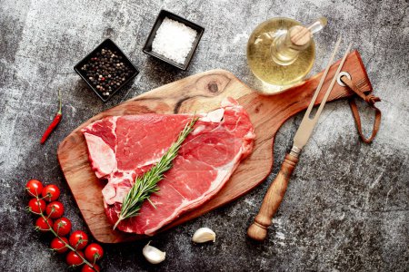 Téléchargez les photos : Steak de bœuf cru avec des épices et des herbes sur une planche de bois. vue de dessus. - en image libre de droit