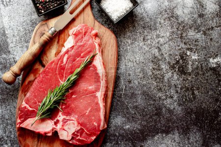 Téléchargez les photos : Steak de bœuf cru avec romarin et épices sur fond de pierre - en image libre de droit