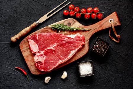 Téléchargez les photos : Steak de bœuf cru aux épices et herbes sur planche de bois - en image libre de droit