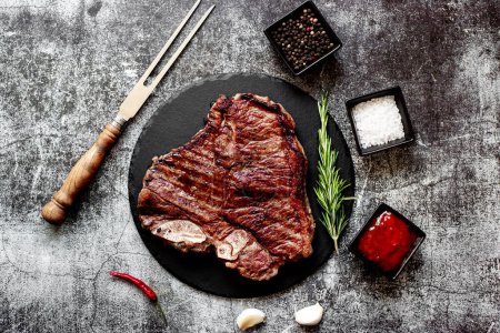 Téléchargez les photos : Steak de bœuf grillé avec romarin et épices sur panneau de pierre noire, vue sur le dessus - en image libre de droit