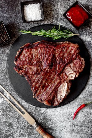 Téléchargez les photos : Steak de bœuf grillé avec romarin et épices sur panneau de pierre noire, vue sur le dessus - en image libre de droit