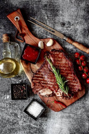 Téléchargez les photos : Steak de bœuf grillé aux épices et romarin sur planche de bois, vue de dessus - en image libre de droit