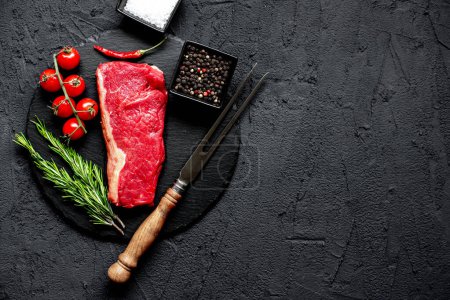 Téléchargez les photos : Steak de bœuf cru aux épices et herbes sur fond de pierre noire - en image libre de droit