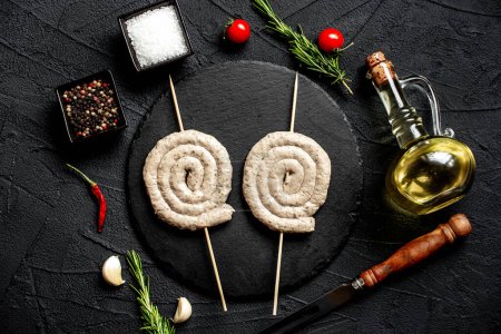Photo for Raw rolled chicken sausages on skewers with spices and herbs, close up view - Royalty Free Image