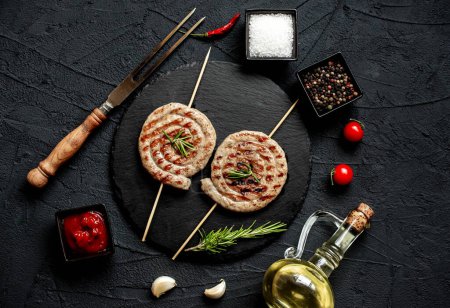 Photo for Grilled rolled chicken sausages on skewers with spices and herbs, close up view - Royalty Free Image