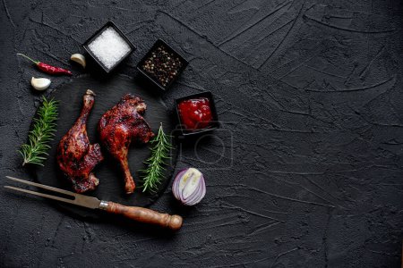 Foto de Grilled chicken legs with spices and herbs on black background - Imagen libre de derechos